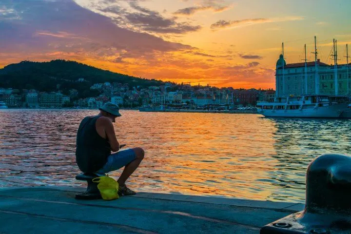 guide to Split Sunsets: where to watch the sunset in split, fisherman watching the sunset from the port