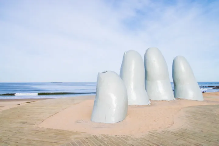 big hand sculpture coming out of the sand 