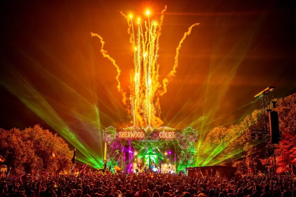 Electric Forest North American music festival with colorful lights illuminating the forest trees at night