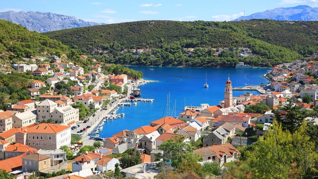 White stone houses reflecting in the crystal clear water of Pučišća harbor on Brač