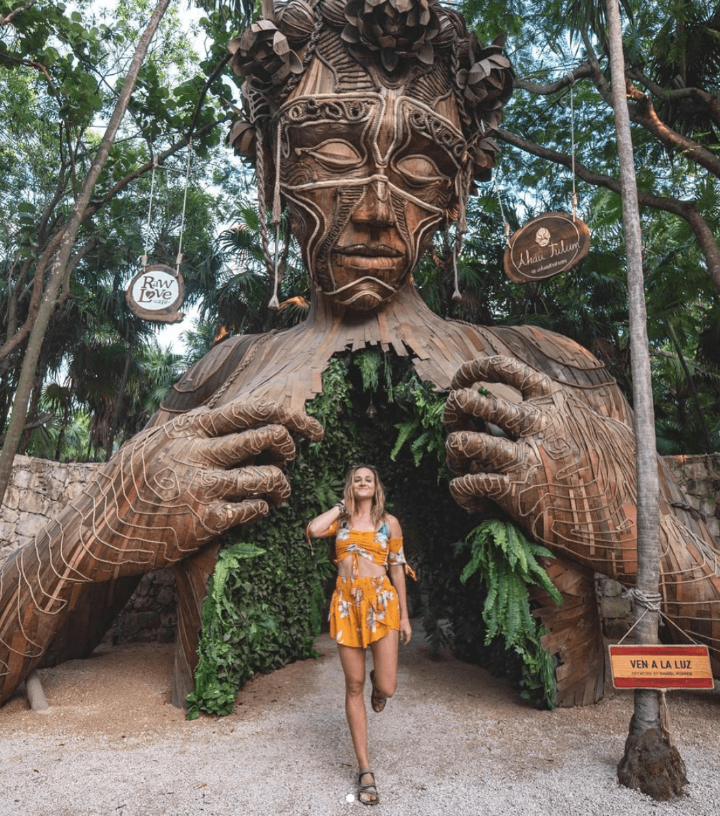 girl in front of statue in Tulum