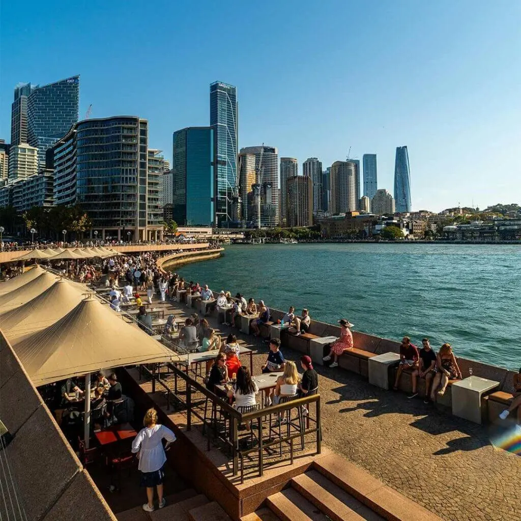 Waterfront view of Circular Quay with ferries, pedestrians and Sydney Harbour landmarks in the background.