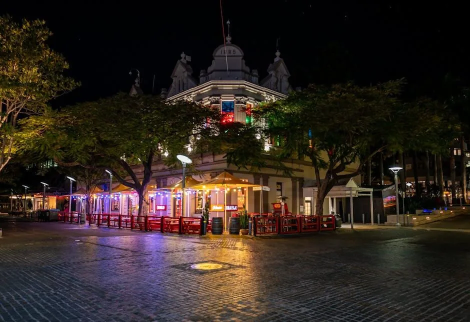A vibrant night scene of an illuminated building in Brisbane with colorful lights and street view.